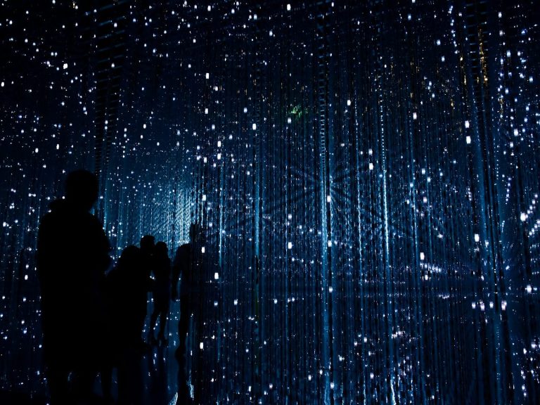 Silhouetten von Personen in einem surrealen, digitalen Raum mit blauen Lichtpunkten.