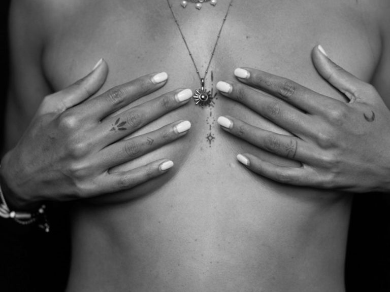 Nahaufnahme einer nackten Oberkörperpartie mit Händen, die die Brust bedecken.