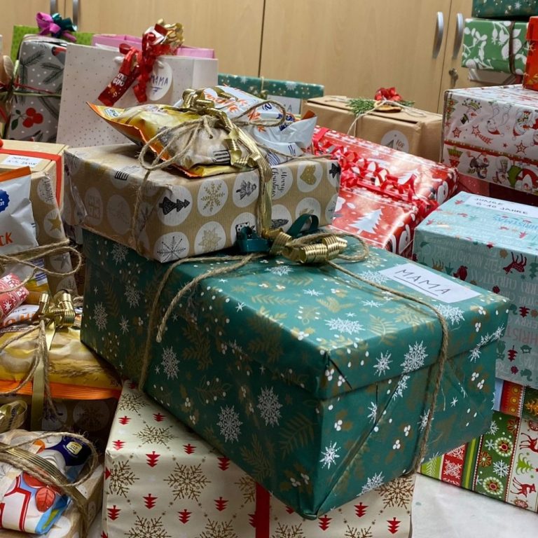 Bild von Frauenhausaktion Geschenkehaufen Bild von Frauenhausaktion Geschenkehaufen: Geschenkstapel in buntem Papier mit Schleifen, auf einem Holzboden verteilt.