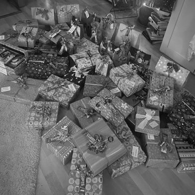 Bild von Frauenhausaktion Geschenkehaufen: Geschenkstapel in buntem Papier mit Schleifen, auf einem Holzboden verteilt.